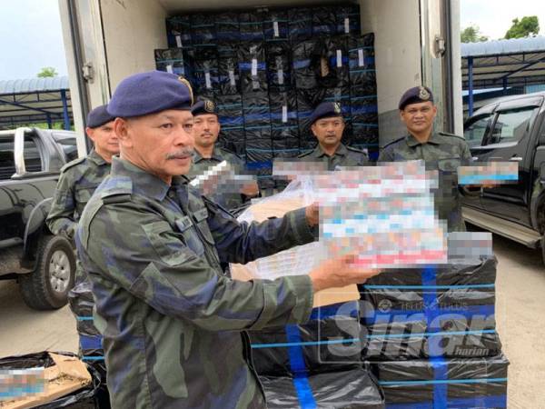 Ab Aziz (depan) menunjukkan rokok seludup yang berjaya dirampas hari ini.