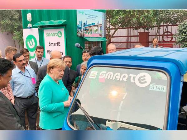 Merkel (tengah) melihat sebuah kenderaan elektrik semasa lawatannya ke stesen kuasa solar di Dwarka, India semalam. - Foto Agensi