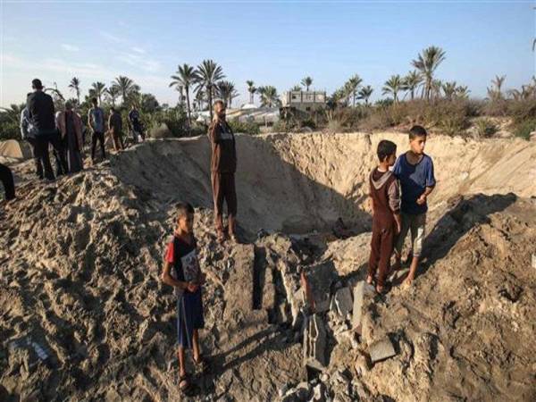 Kanak-kanak Palestin berdiri di satu lokasi di Khan Yunis yang menjadi serangan udara Israel pada Jumaat lalu. -Foto AGENSI