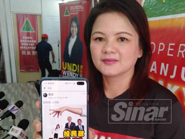 Naib Presiden Gerakan, Janice Wong Oi Foon menunjukkan poster diedar melalui laman sosial menunjukkan Wendy menjadi boneka kepada PH.