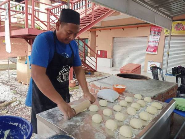 Badrul Jamili menyiapkan roti tempayan yang dipesan pelanggan.