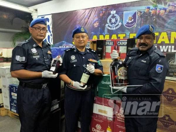 Tiga anggota PPMW2 menunjukkan minuman keras yang dirampas dalam operasi berkenaan.