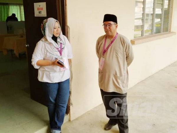 Badhrulhisham (kanan) berbual bersama calon Bebas, Faridah Aryani Abdul Ghaffar di IPD Pontian, lokasi pengundian awal bagi PRK Parlimen Tanjung Piai.