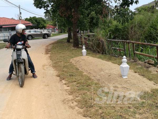 Seorang penduduk berhenti seketika untuk melihat 'kubur' yang dibina itu.