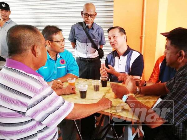 Jeck Seng (duduk, tengah) berkata sesuatu pada sebahagian pemandu teksi di terminal teksi di terminal bas Pontian hari ini.