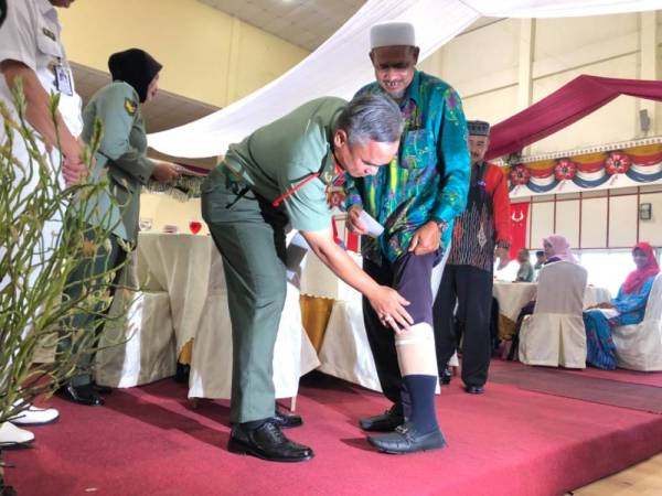 Muhammad Huzaimi melihat kaki palsu yang dipakai seorang bekas pegawai tentera, Zarawi Muhammad, 62, yang kudung paras lutut selepas terkena jerangkap samar ketika Perang Gerilla pada tahun 1977.