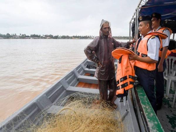 Muhd Nur Syam Asmawie (dua dari kanan) menasihati Mahadi Mahmud, 42, agar menggunakan jaket keselamatan ketika melakukan aktiviti sungai pada Program Pertemuan APMM Kelantan Bersama Penduduk di Pulau Muara Sungai Kelantan Untuk Persiapan Banjir hari ini. - Foto Bernama