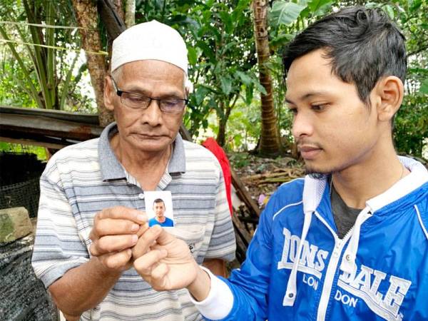 Mohamed (kiri) dan Zulhafizan melihat gambar Zarawi yang tersimpan dalam dompetnya.