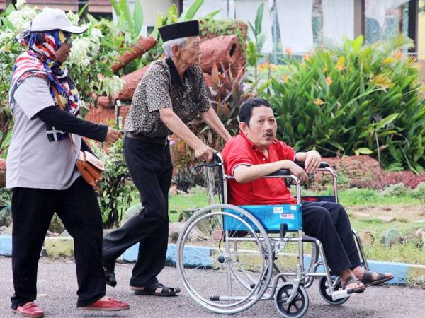 Pengundi orang kurang upaya (OKU), Zulkifli Sadiman, 56, (kanan) dibantu bapanya Sadiman Mortomo, 81, (tengah) untuk mengundi di saliran satu bagi PRK Tanjung Piai di SMK Dato' Mohd Yunus Sulaiman, Pekan Nanas hari ini. - Foto Bernama