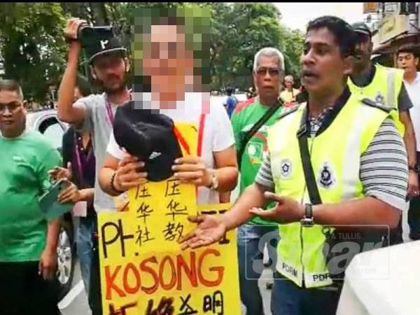 Lelaki yang memakai plakad yang mencetuskan kekecohan di hadapan pusat mengundi Sekolah Jenis Kebangsaan Cina Yu Ming. - Foto SHARIFUDIN ABDUL RAHIM