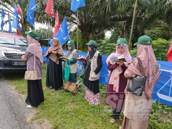 Kelihatan beberapa penyokong parti Berjasa khusyuk membaca al-Quran bagi mendoakan kemenangan calon parti itu, Ir Badrulhisham di luar pekarangan PDM di Sekolah Kebangsaan (SK) Teluk Kerang, Pontian hari ini.