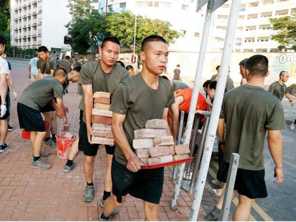 Anggota PLA membantu membersihkan jalan di luar pangkalan mereka. - FOTO: AFP