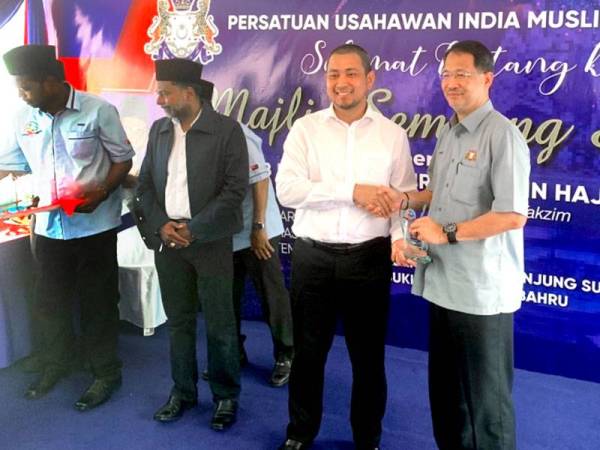 Sahruddin (tengah) ketika menyampaikan sijil penghargaan kepada salah seorang wakil jabatan kerajaan pada majlis perasmian pejabat dan sembang santai Persatuan Usahawan India Muslim Negeri Johor (Perusim) di Taman Bukit Alif hari ini.