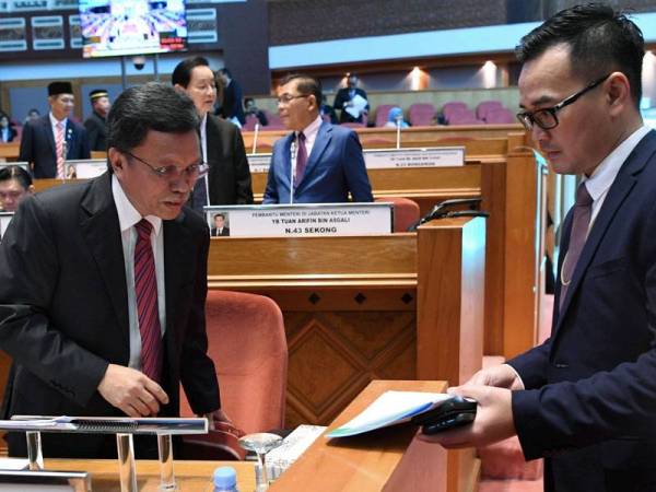 Mohd Shafie (kiri) meneliti fail yang diserahkan oleh Setiausaha Sulit Ketua Menteri Sabah, Francis Au (kanan) sebelum persidangan bermula di DUN Sabah hari ini. - Foto Bernama