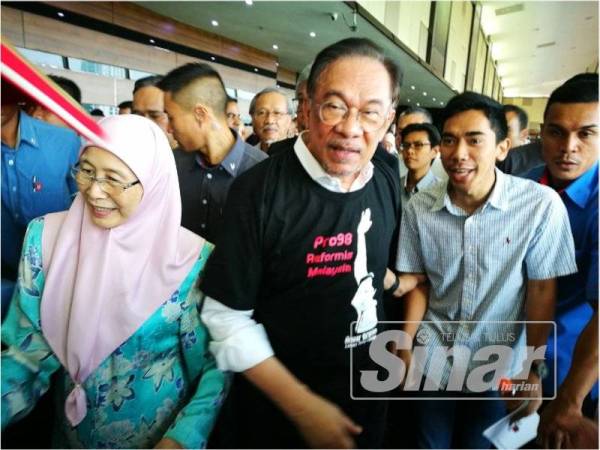 Anwar bersama Wan Azizah diiringi pegawai keselamatan dan penyokong sejurus keluar dari IDCC hari ini.