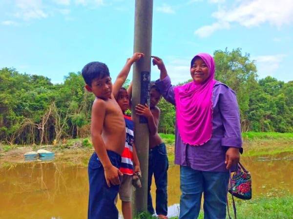 Rohani (kanan) menunjukkan paras air setiap kali kampung mereka dilanda banjir.