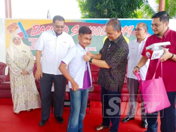 Amiruddin (tiga dari kanan) memakaikan uniform sekolah kepada seorang pelajar sebagai simbolik perasmian Back to School 2019 di Dewan Terbuka, Masjid Hidayatol Solihin, Sungai Baru Gunong, Alor Setar hari ini.