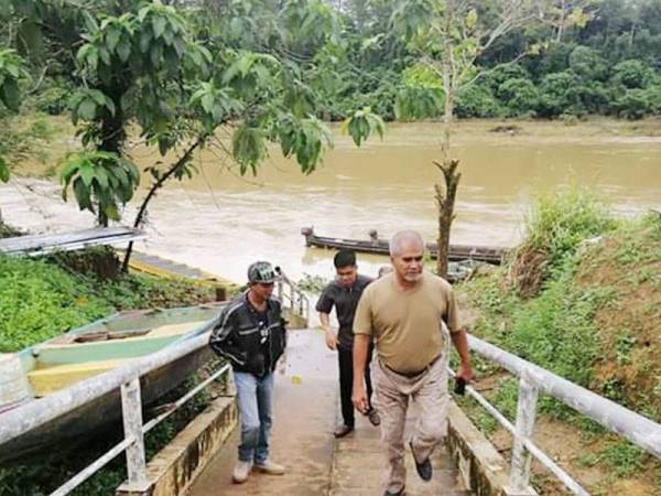 Nazri (kanan) meninjau keadaan jambatan gantung di Kampung Pagi yang rosak akibat banjir.