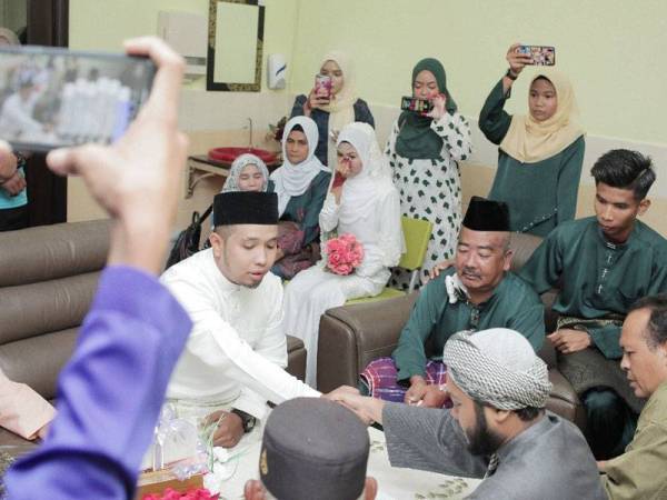 Nurul Ain tidak dapat menahan sebak ketika majlis akad nikahnya di HTJ disaksikan ayahnya (duduk berbaju hijau). -Foto ihsan pengantin