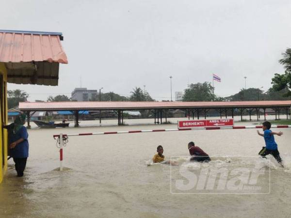 Kanak-kanak bermain air banjir di Rantau Panjang.