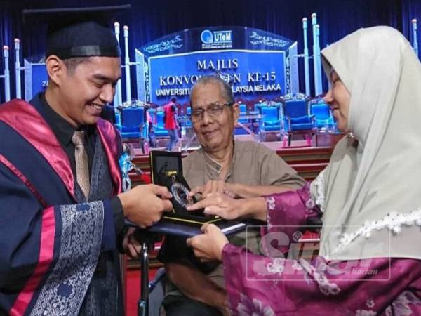 Amirul Zarith (kiri) menunjukkan anugerah diterima kepada kepada ibu bapanya pada Majlis Konvokesyen Universiti Teknikal Malaysia Melaka (UTeM) Ke-15 di Dewan Canselor Kampus Induk UTeM, Durian Tunggal hari ini.