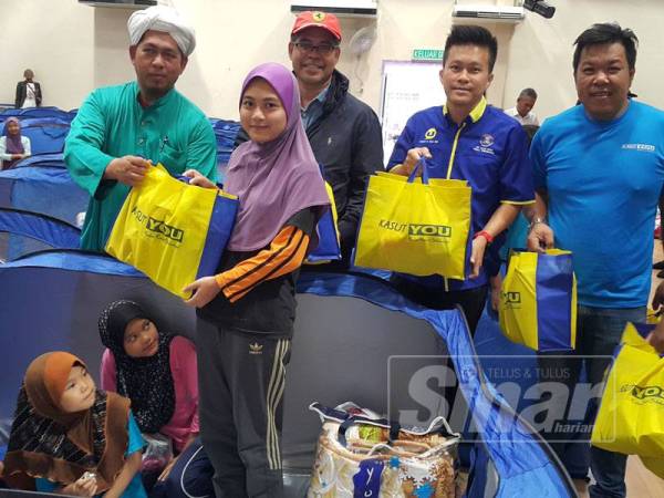 Mohd Sophian (tiga dari kiri) dan Raymond (empat dari kiri) menyampaikan sumbangan kepada mangsa yang terjejas banjir di Perpustakaan Awam Permaisuri hari ini.