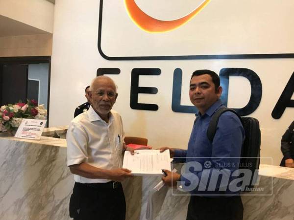 Shahir (kiri) menerima penyerahan writ dan tuntutan saman Felda daripada peguam agensi kerajaan itu di ruang legar Menara Felda hari ini.