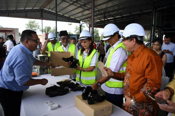 Teresa melihat kasut yang dihasilkan daripada pokok kenaf ketika merasmikan Pusat Industri Kenaf di Kampung Tebu Hitam hari ini. Turut hadir Wan Abdul Rahim (empat dari kanan) dan Samsudin (dua dari kanan). -Foto Bernama