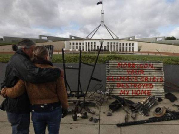 Plesman bersama pasangannya membawa sisa serpihan rumah mereka yang musnah terbakar di luar bangunan Parlimen di Canberra kelmarin. - Foto Agensi