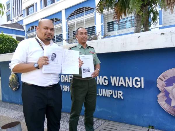 Izmil (kiri) menunjukkan laporan polis di hadapan Ibu Pejabat Polis Daerah Dang Wangi.