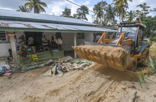 Jentolak digunakan bagi membersihkan kawasan rumah penduduk dan jalan yang rosak selepas dilanda banjir ketika tinjauan di Kampung Chuchuh Puteri A hari ini. -Foto Bernama