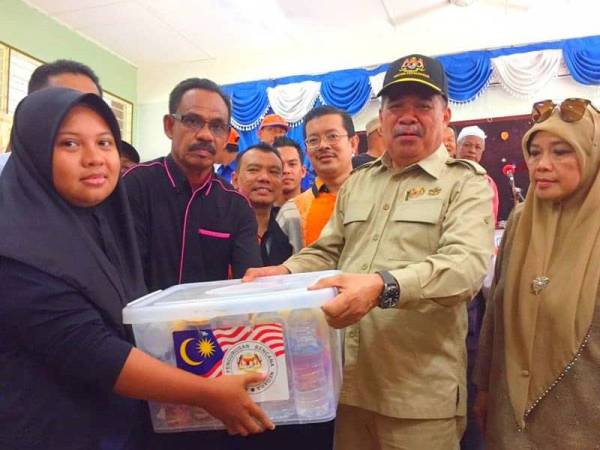 Mohamad (dua dari kanan) menyampaikan sumbangan kepada mangsa-mangsa banjir di PPS Sekolah Menengah Kebangsaan Agama (SMKA) Lati.