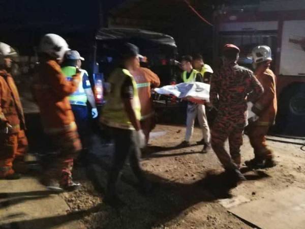 Anggota bomba mengangkat mayat mangsa yang rentung untuk dibawa ke Unit Forensik HTAA bagi tujuan bedah siasat.