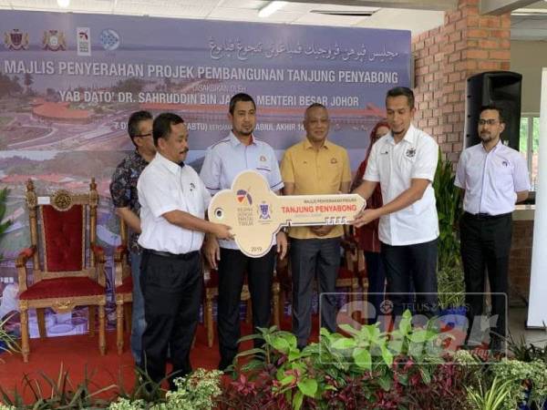 Sahruddin (dua dari kiri) dan Baidzawi (kiri) menyampaikan replika kunci kepada Yang Dipertua Majlis Daerah Mersing, Norazmi Amir Hamzah.