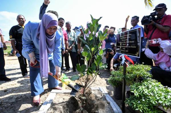 Rina menanam pokok cempedak madu sambil disaksikan para penduduk desa Lembaga Kemajuan Wilayah Kedah (KEDA) Teluk Berembang pada program pembangunan yang dilaksanakan di Pulau Tuba hari ini. -Foto Bernama