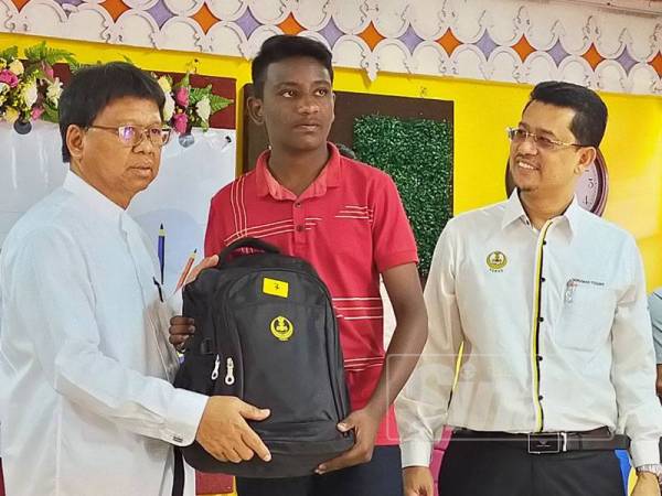 Asmuni (kiri) menyerahkan set kelengkapan sekolah kepada salah seorang pelajar pada Majlis Penyerahan Sumbangan 'Back To School' dan Biasiswa Menteri Besar Perak di Manjoi hari ini.