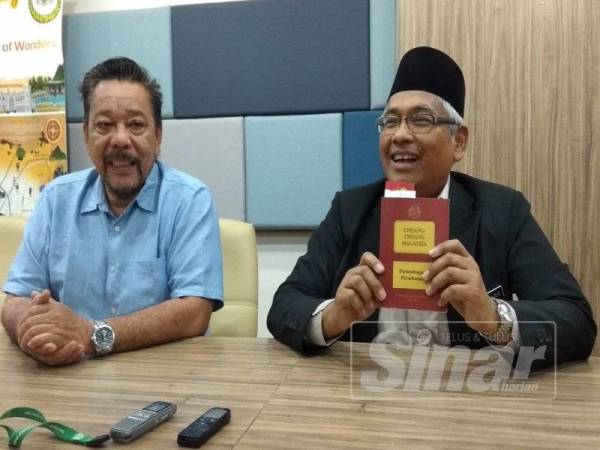 Abdul Aziz menunjukkan buku Perlembagaan Persekutuan yang menyebut bahawa isu berkaitan tanah terletak di bawah bidang kuasa kerajaan negeri pada sidang media hari ini.