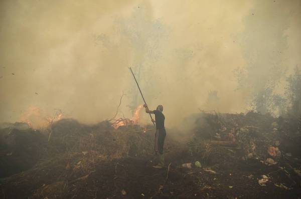 Seorang penduduk kampung cuba memadamkan kebakaran di sebuah perkampungan di Kampar, Riau pada September lalu. - Foto: AFP
