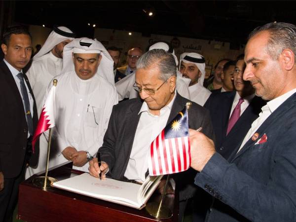 Dr Mahathir (tengah) menandatangani buku lawatan ketika hadir melawat Ladang Baladna hari ini. Turut kelihatan, Menteri Perdagangan dan Industri Qatar Ali Ahmed Al Kuwari (dua,kiri). -Foto Bernama