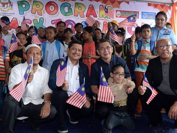 Salahuddin (dua, kanan) bergambar bersama penerima bantuan peralatan sekolah ketika hadir pada Program Jom Ke Sekolah di A Mart Kempas hari ini. -Foto Bernama