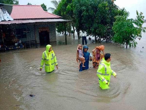 Penduduk kampung di Rompin diiringi anggota keselamatan berpindah selepas kampung mereka dinaiki air banjir semalam. Foto: Bernama