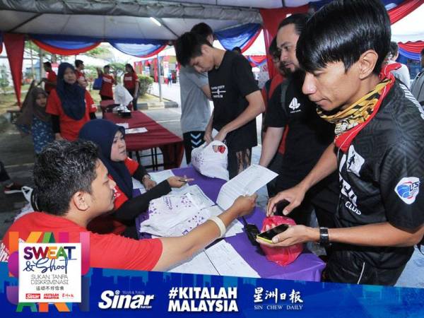 Peserta Sweat & Shoot Sukan Tanpa Diskriminasi mendaftar sebelum perlawanan bermula.