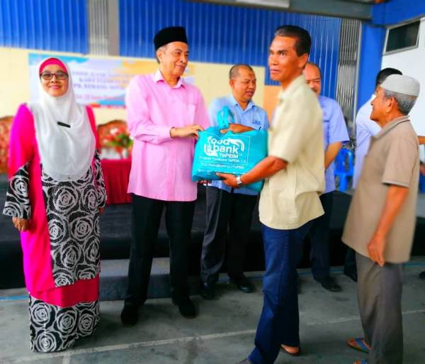 Rohana (kiri) dan Husam (dua dari kiri) menyampaikan sumbangan kepada penerima di PPK Kubang Sepat di sini hari ini.