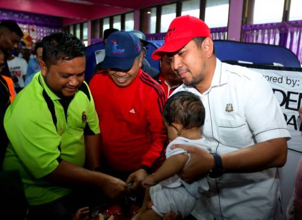 Sahruddin (kanan) bersama Farizal Ismail (dua dari kiri) beramah mesra bersama mangsa banjir ketika hadir melawat Pusat Pemindahan Banjir (PPS) SK Sedili Kecil, Kota Tinggi hari ini. - Foto: Bernama
