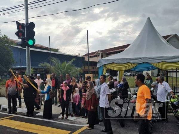 Azrul (dua dari kiri) merasmikan lampu isyarat lintasan pejalan kaki SK Teluk Kumbar semalam.