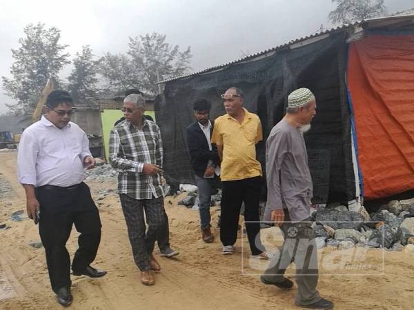 Hanafiah (dua dari kiri) meninjau keadaan hakisan yang berlaku di Pantai Kuala Kemasik hari ini.