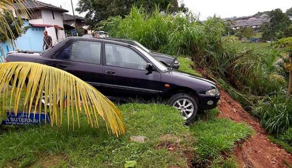 Dua kenderaan yang diletakkan berhampiran tebing jalan di Jalan Sutera 6/1 Taman Sentosa Saleng dekat Kulai hampir terjatuh berikutan tanah runtuh pada 4.49 petang tadi hari ini. -Foto Bernama