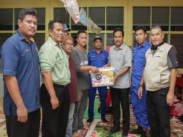 Mohd Zakaria (tiga dari kanan) menyampaikan sumbangan kepada mangsa banjir di PPS Kampung Setajam, Rompin. - Foto Ihsan Media Pahang