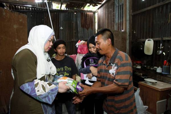 Rina (kiri) menyampaikan sumbangan bantuan berasaskan barangan dapur kepada Shamsul Kamal Abd Hamid, 49, (kanan) dan baucar bantuan persekolahan kepada Nur Ardina Sofea,17, (dua dari kanan) pada program Back To School di Taman Perpaduan Tambun hari ini. -Foto Bernama