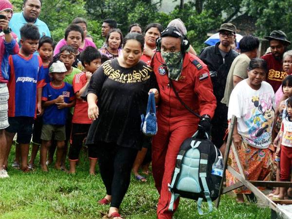 Anggota Unit Udara JBPM, Safuan Mohamad (kanan) melalui misi sukar apabila terpaksa melakukan penerbangan ihsan dalam keadaan cuaca yang tidak mengizinkan bagi membawa keluar tiga ibu mengandung orang asli di Kampung Peta dekat Endau. - Foto Bernama